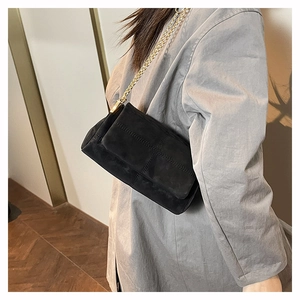 Detail of black suede rectangular crossbody bag with gold chain strap and stitching