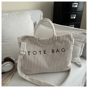 Close-up of beige corduroy tote bag showing textured fabric and TOTE BAG embroidery