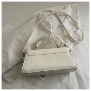 Close-up of a cream white crossbody bag on knitted fabric with refined stitching detail