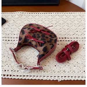 Detail of leopard print crescent bag with red leather bows and white lace trim edge