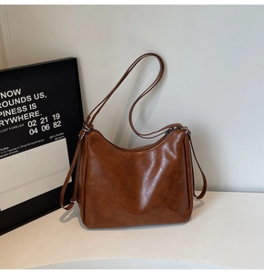 Detail of caramel brown hobo bag in soft leather with silver zipper and slim strap