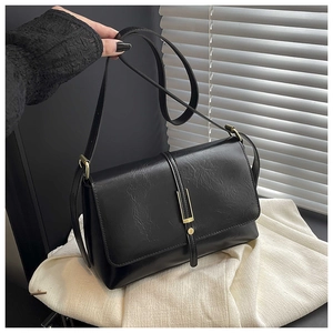 Détail du sac bandoulière noir avec boucle en métal doré et texture en similicuir lisse