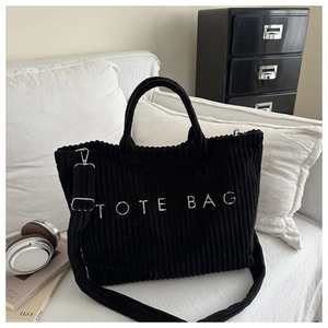 Detail of black corduroy tote bag with TOTE BAG embroidery and adjustable shoulder strap