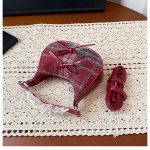 Detail of red plaid crescent bag with leather bows and delicate white lace trim