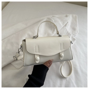 Detail of white leather handbag showing vertical stitching and silver metal hardware