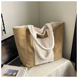 Detail of camel suede and white sherpa tote bag on a desk with a laptop and magazine