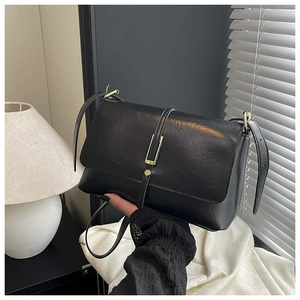 Détail d'un sac bandoulière vintage noir avec garniture dorée et texture cuir
