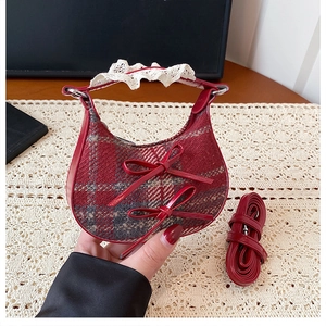 Detail of red plaid crescent bag with decorative bows and delicate lace-wrapped handle