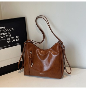 Detail view of a vintage brown hobo bag featuring decorative zippers and smooth leather finish