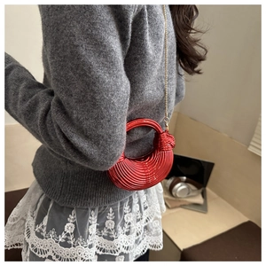 Dettaglio di una borsa a conchiglia in acrilico rosso a righe con catena oro