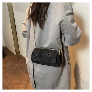 Detail of black rectangular crossbody bag with matte finish and gold metal corners