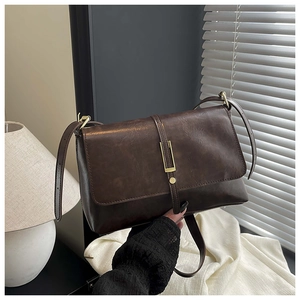 Détail du sac bandoulière vintage marron foncé avec boucle métallique dorée élégante