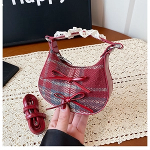Detail of red plaid crescent bag featuring dual bows and delicate lace trim handle