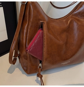 Close-up of brown leather tote with metal zipper pocket and adjustable shoulder strap