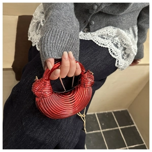 Dettaglio borsa in acrilico rosso con texture a spirale e nodo decorativo sul manico
