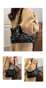 Detail of black glossy wax leather tote bag with metal eyelets and strap buckle accents
