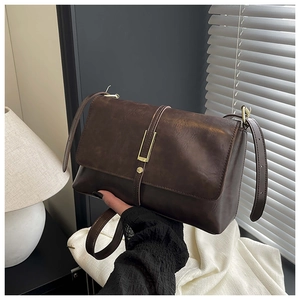 Détail du sac bandoulière vintage marron avec boucle dorée et texture en cuir mat
