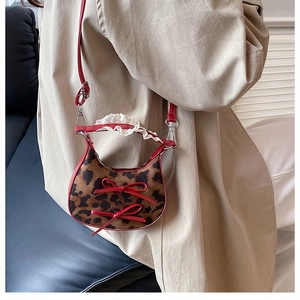 Detail of mini leopard print handbag with red bows and white lace handle decoration