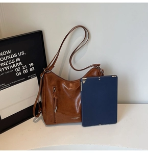 Close-up of brown vintage leather bag showing glossy texture and fashion brand logo