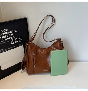 Detail of a brown vintage leather tote bag next to a tablet showing scale and texture