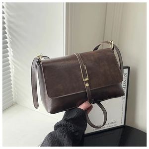 Sac bandoulière rétro marron foncé avec boucle dorée sur un fond artistique minimaliste