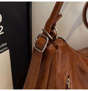 Close-up of vintage brown leather tote with silver metal buckle and zipper detail