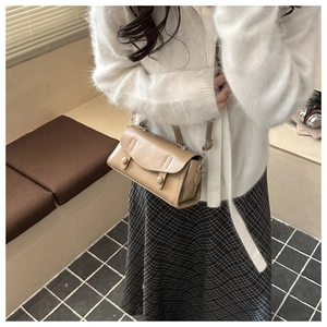 Detailed view of milk tea brown crossbody bag featuring dual decorative buttons on matte leather