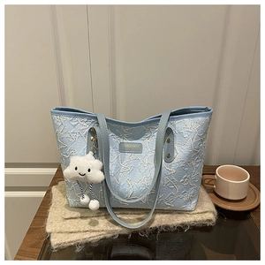 Close-up of light blue quilted tote bag with star stitching and a plush cloud charm