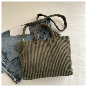 Vue à plat d'un sac cabas en velours côtelé vert foncé avec poignées et bandoulière