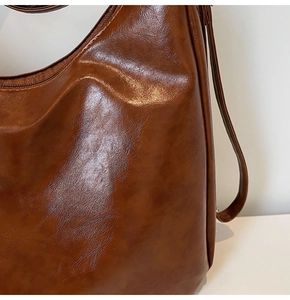 Detailed view of the dark brown glossy faux leather texture and retro pleated finish