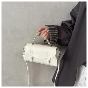 Detail of a creamy white leather handbag with silver buckles and fine stitching details