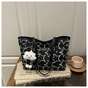 Macro detail of black quilted tote bag with star patterns and cloud plush charm
