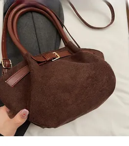 Close-up of brown suede bucket bag featuring soft texture and gold hardware details