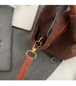 Detail of golden hardware and brown suede texture on a trendy crossbody handbag