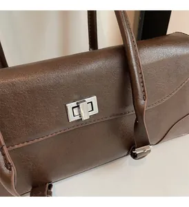 Close-up of brown leather texture and silver metal lock on a vintage underarm bag