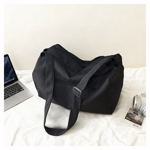 Large black fitness bag with adjustable straps near laptop and headphones on fabric
