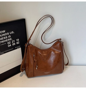Detail of vintage brown leather tote bag showing vertical zipper and gold foil branding