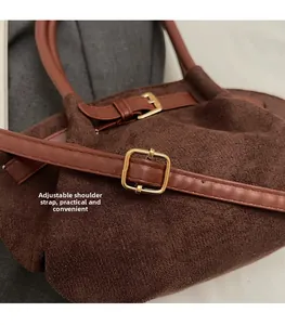 Macro detail of dark brown faux suede bag featuring adjustable strap and gold metal buckle