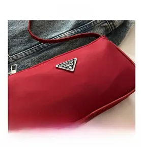 Close-up of red nylon bag with silver triangular logo plaque on denim background