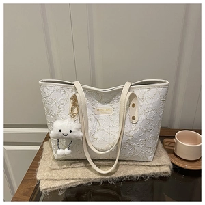 Close-up of white quilted tote bag with campus leather patch and plush cloud charm