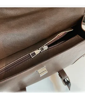 Detail view of smooth silver zipper closure on a vintage dark brown leather bag