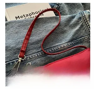 Detail of red nylon shoulder bag with triangle logo and metallic zip on denim background