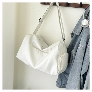 Detailed view of the white sports duffel bag with zipper pockets hanging on a wooden hook