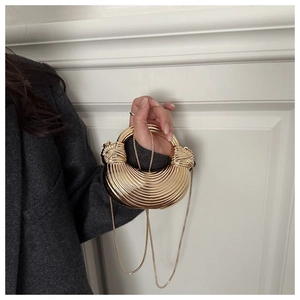 Détail d'un sac demi-lune doré avec texture nervurée, poignée nouée et bandoulière chaîne
