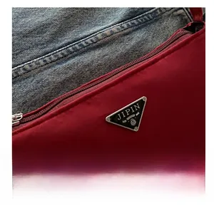 Close-up of the burgundy nylon texture with metal zipper and triangular logo detail