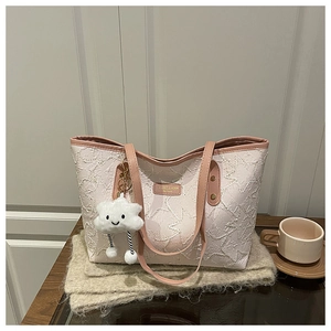 Detail of star-textured tote bag with pink leather straps and white cloud plush charm