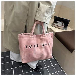 Détail du cabas en velours côtelé rose avec broderie TOTE BAG noire et textures verticales