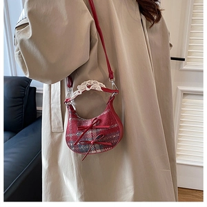 Detail of red plaid crescent bag with bow accents and lace trim on model
