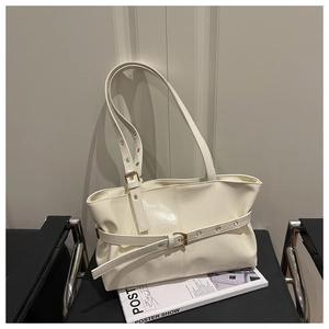 Detail view of cream vintage shoulder bag with buckle strap on a minimalist chair