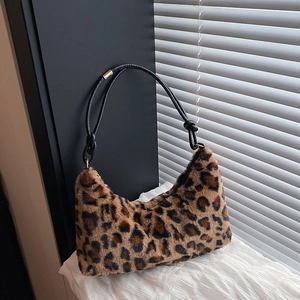 Large leopard print plush tote bag with black faux leather straps in a crescent shape
